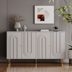 a white sideboard with gold legs in a living room next to a potted plant