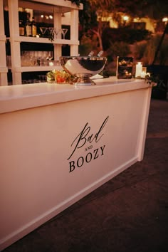 a bar and boozy sign on the side of a building at night with lights in the background