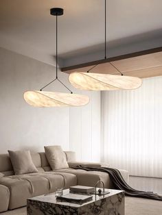 a living room with couches, tables and lamps hanging from the ceiling above them