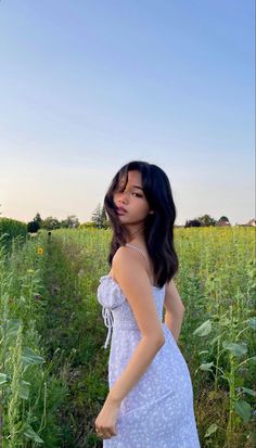 a woman standing in a field with tall grass