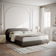 a bedroom with white walls and wood flooring has a large bed in the middle