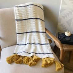 a white and black blanket sitting on top of a chair next to a wooden chair