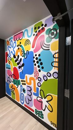 a large colorful painting on the side of a wall next to a doorway in an office building