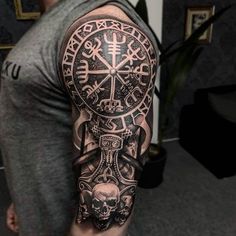 a man with a black and grey tattoo on his arm, holding a clock in his hand