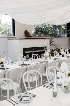 tables and chairs are set up for an event with white linen draped over the fireplace