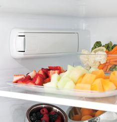 fresh fruits and vegetables are on the shelves of an open refrigerator, ready to be eaten