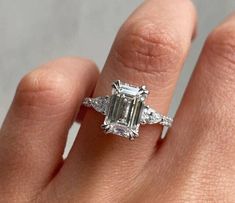 a woman's hand with a ring on it and an emerald stone in the middle