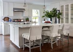 a large kitchen with white cabinets and an island in front of the stove top oven