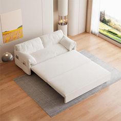 a white couch sitting on top of a hard wood floor next to a large window