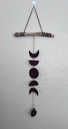 a wind chime hanging from the side of a wall with three moon phases on it