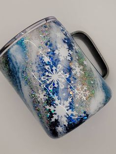 a blue and white flask with snowflakes on it sitting on a table