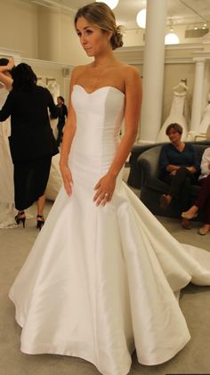 a woman standing in front of a dress on display