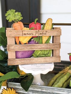 a wooden crate filled with fresh vegetables on top of a metal tray next to sunflowers