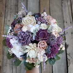 a bouquet of flowers in a vase on a wooden table with planks behind it