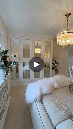 a large white bed sitting inside of a bedroom next to a chandelier hanging from the ceiling