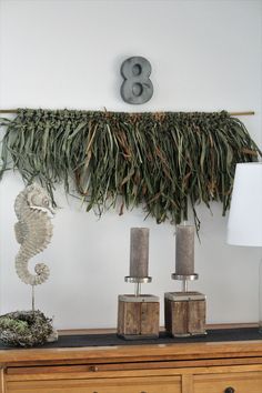 a table with two candles on top of it and some plants hanging from the wall