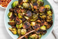 a bowl filled with brussel sprouts next to a spoon