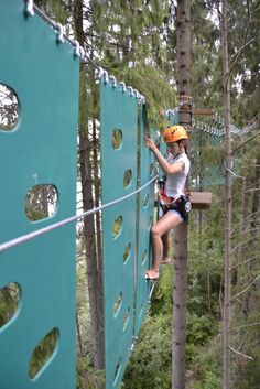 a person on a rope course in the middle of a forest with trees and ropes