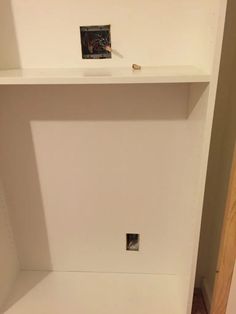 a white shelf with pictures on it in a room next to a wall and door