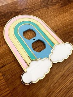 a wooden cut out of the letter d with clouds and rainbows on it sitting on a table