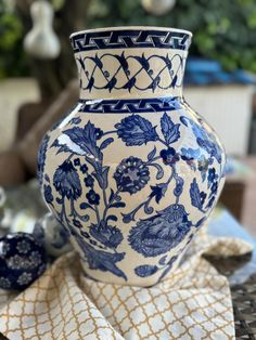 a blue and white vase sitting on top of a table next to a cloth covered bowl