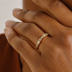 a woman's hand wearing a gold ring with three small diamonds on the band