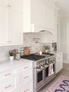 a kitchen with white cabinets and stainless steel stove top oven in the center of the room