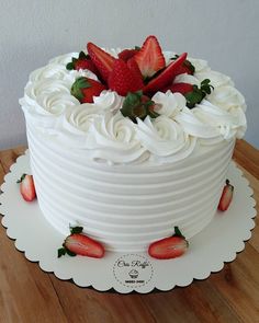 a white cake topped with strawberries on top of a wooden table