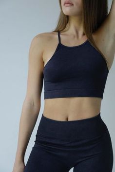 a woman in black sports bra top and leggings with her hand on her head