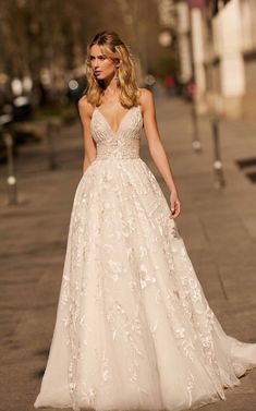 a woman is walking down the street wearing a wedding dress with floral appliques