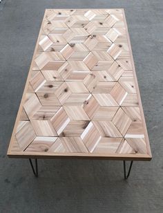 a coffee table made out of wood with geometric designs on the top and metal legs