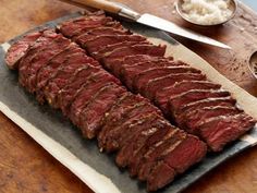 a large piece of meat sitting on top of a cutting board next to a knife