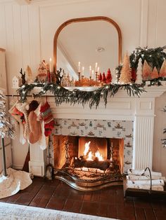 a fireplace decorated for christmas with stockings and candles