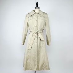 Vintage 1970's hooded trenchcoat in cream Features six functional buttons down the front, a removable sash belt, removable hood, removable liner, has spacious pockets & buttons on the sleeve cuffs Good condition with no real wear Measurements  Bust - 21" flat  Length - 41" Sleeve length - 29" Contents  Shell - 100% Acrylic Liner - 100% Polyester Please message with any questions ❤️ Retro Khaki Outerwear For Spring, Vintage Beige Outerwear With Flap Pockets, Vintage Beige Collared Outerwear, Vintage Long Sleeve Belted Outerwear, Vintage Beige Outerwear With Snap Buttons, Retro Beige Outerwear For Spring, Spring Beige Raincoat With Pockets, Retro Beige Spring Outerwear, Retro Beige Long Coat