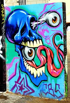 graffiti on the side of a building with a blue skull and red snake biting it's mouth