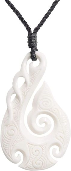 a white pendant with an intricate design on a black cord necklace hanging from a string