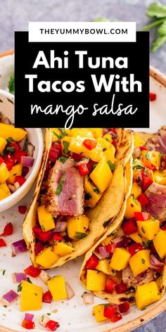 two tacos on a plate with mango salsa in the background and text overlay that reads ahi tuna tacos with mango salsa