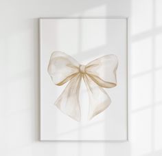 a white framed art print with a large bow on it's side, hanging on a wall