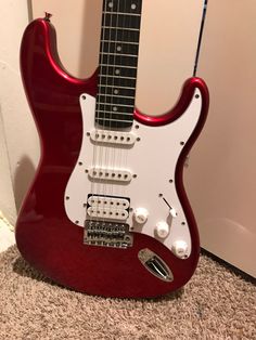 a red electric guitar sitting on the floor