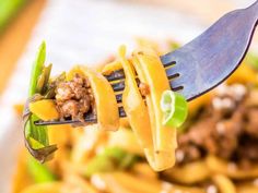 a fork full of noodles with meat and vegetables