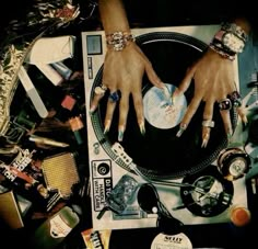 two hands on top of a record player surrounded by assorted jewelry