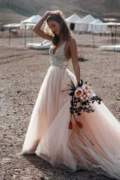 a woman in a long dress holding a bouquet and posing for the camera with her hand on her head