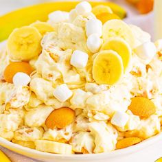 a bowl filled with fruit and marshmallows on top of a table next to bananas