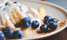 a white plate topped with bananas and blueberries next to ice cream on top of it