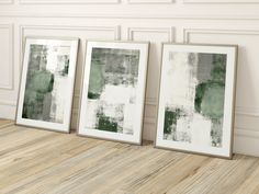 three framed art pieces sitting on top of a wooden floor