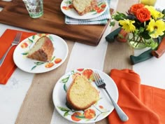 two plates with slices of cake on them sitting on a place mat next to flowers