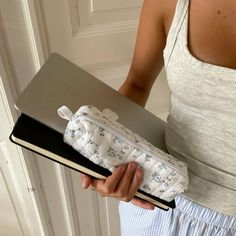 a woman holding an open laptop computer case in her left hand, with the cover partially closed