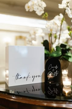 a couple of cards sitting on top of a wooden table next to candles and flowers