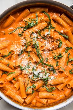 a pan filled with pasta and sauce covered in parmesan cheese