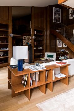 a living room filled with furniture and bookshelves next to a stair case in the background